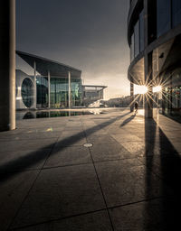 City street by building against sky during sunset