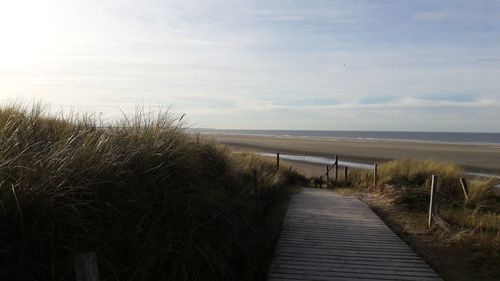 Boardwalk by sea against sky