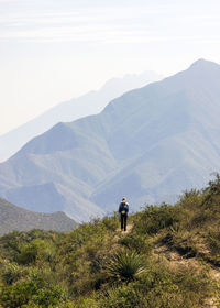 Rear view of man looking at mountains against sky