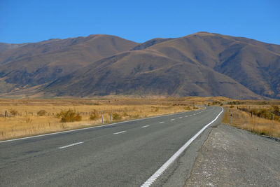 Road leading towards mountains against sky