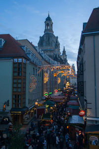 People on street amidst buildings in city at dusk