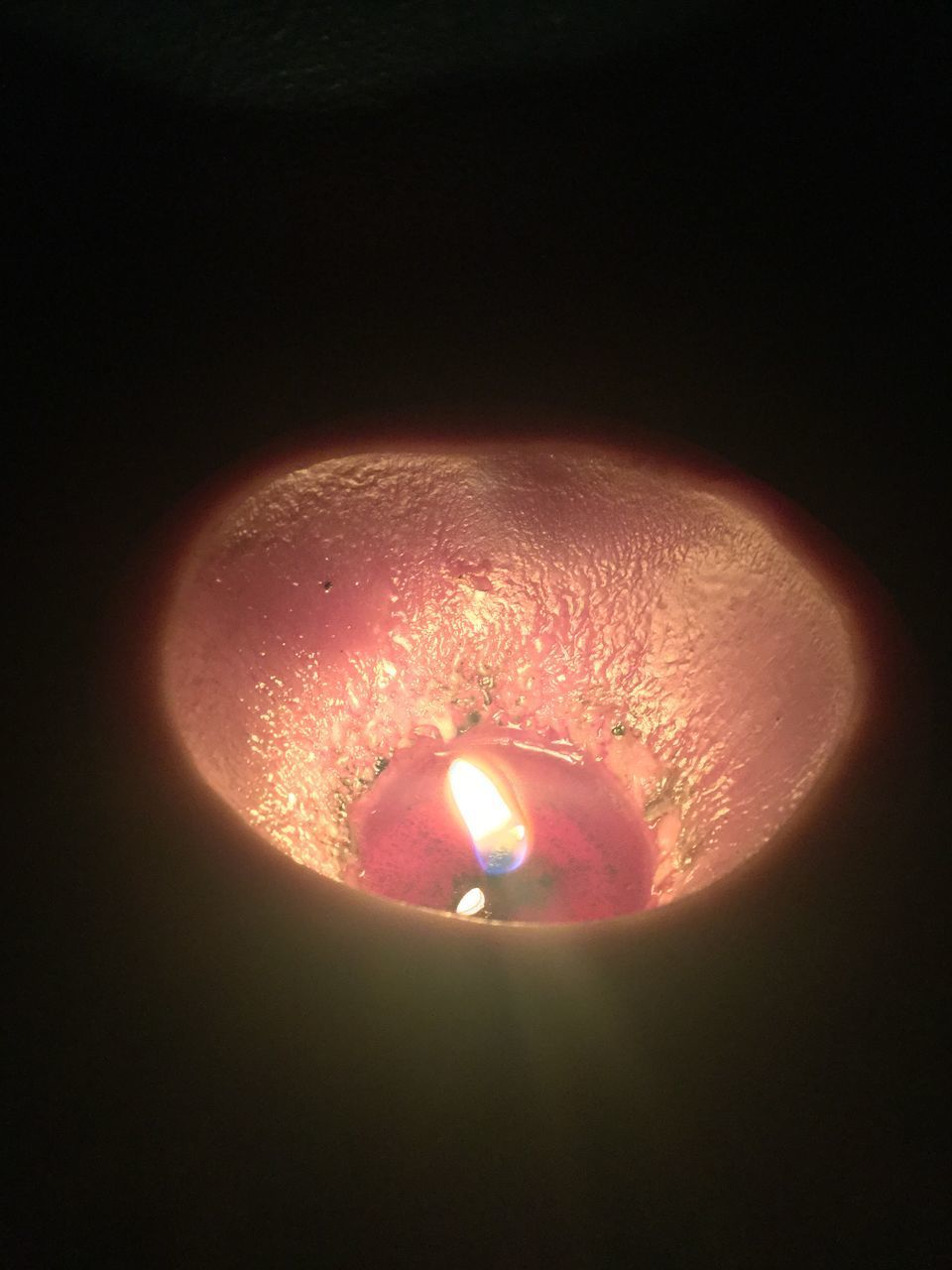 CLOSE-UP OF LIT CANDLE ON BLACK BACKGROUND