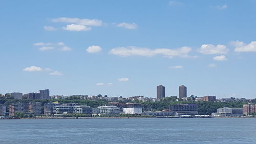 City at waterfront against cloudy sky