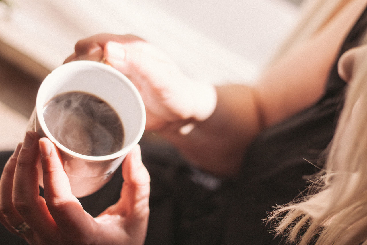 MIDSECTION OF WOMAN DRINKING COFFEE