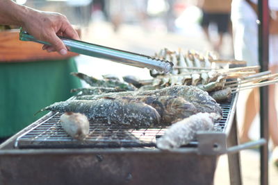 Close-up of man preparing food on barbecue grill