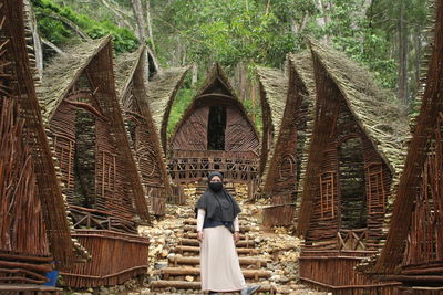 Rear view of woman standing outside temple against building