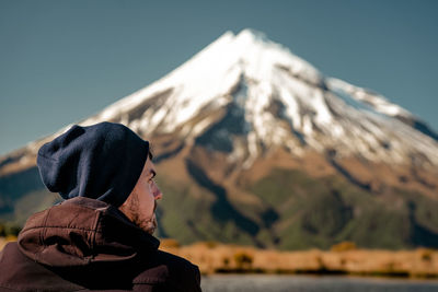Side view of woman looking at mountain against sky