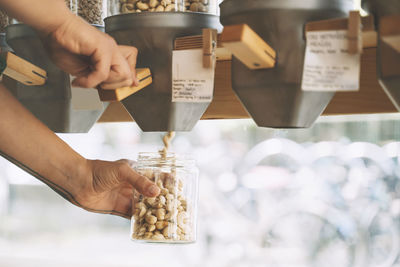 Woman's hand filling cashews in jars at shop