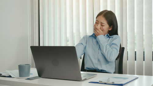 Young woman using mobile phone while sitting on table