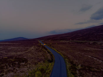 Scenic view of road leading towards mountains against sky