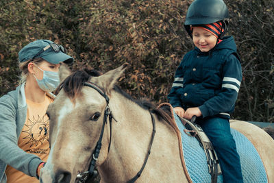 Girl sitting on horse against trees