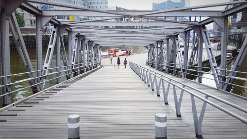 Rear view of people walking on footbridge in city