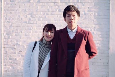 Couple standing against brick wall