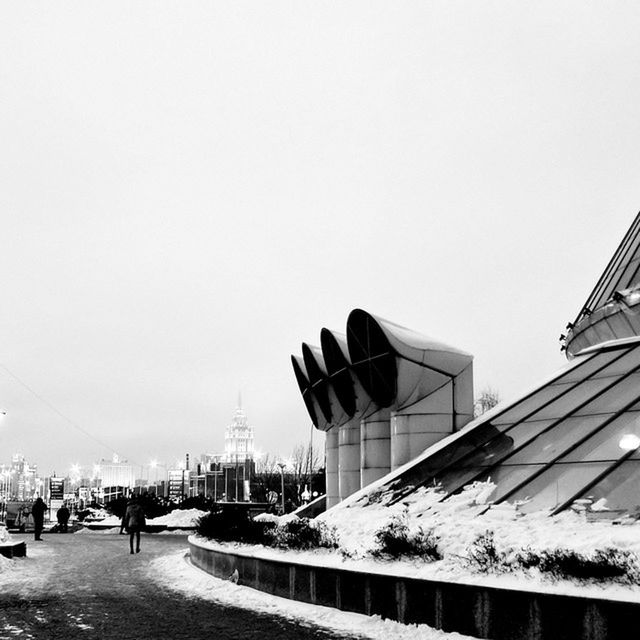 clear sky, built structure, architecture, building exterior, copy space, transportation, winter, snow, road, city, day, incidental people, outdoors, cold temperature, season, street, street light, low angle view, sky, the way forward