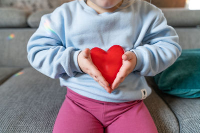 Midsection of woman holding heart shape