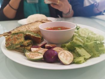 Close-up of person preparing food in plate on table