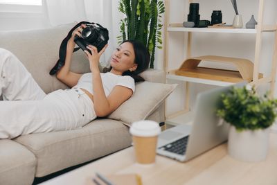 Young woman using mobile phone while sitting on sofa at home