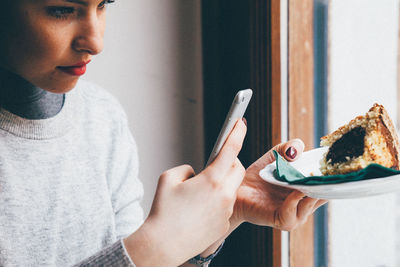 Woman photographing pastry with mobile phone