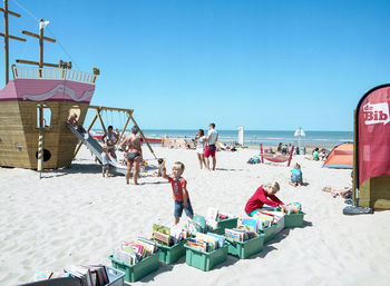 People on beach against clear sky