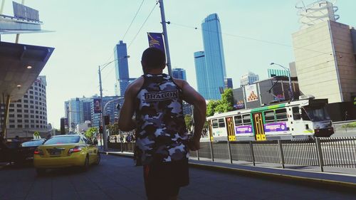 Rear view of man standing in city against sky