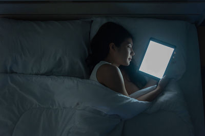 Young woman using mobile phone on bed at home