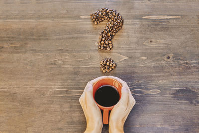 Directly above shot of hand holding coffee cup on table