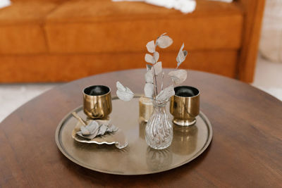 Gold glasses, dried flowers in a vase on a round tray on the coffee table