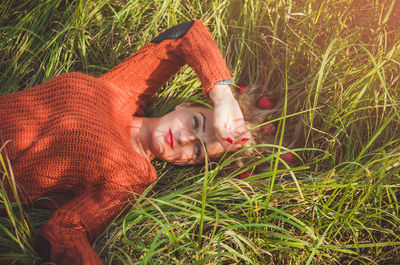 High angle portrait of woman lying with apples on grassy field