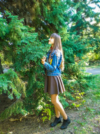 Full length of woman standing by tree