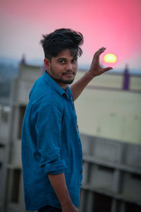 Portrait of young man standing against blue wall