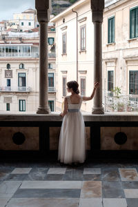 Rear view of woman standing by building in city