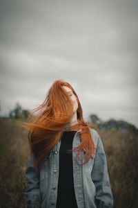 Rear view of woman with umbrella standing against sky