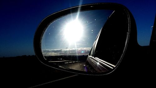 Close-up of reflection of sky on side-view mirror of car