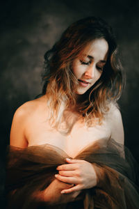 Portrait of young woman standing against black background