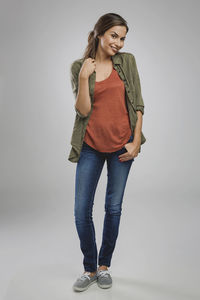 Portrait of young woman standing against white background