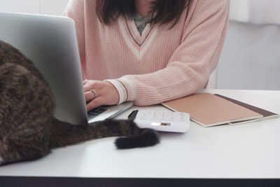 Midsection of woman using mobile phone while sitting on table