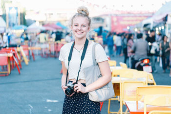 Portrait of smiling young woman standing in city