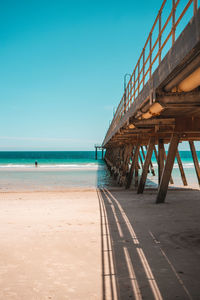 Pier on beach against clear sky