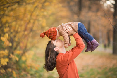 Mother with child in her arms against background of autumn. family mom and baby walk in park. 