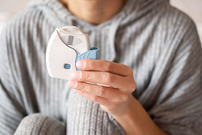 Woman use asthma inhaler at home, close up.