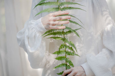 Woman holding plant while sitting outdoors