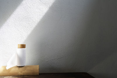 Close-up of white bottle against wall at home