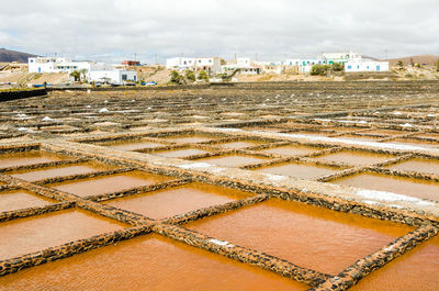 Salt flats by houses against sky