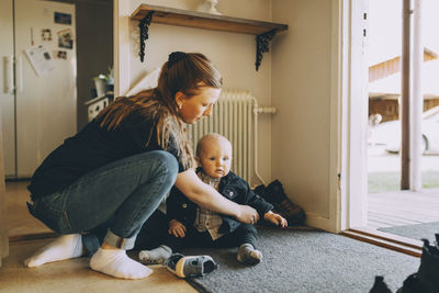 Mother getting son dressed sitting on doormat