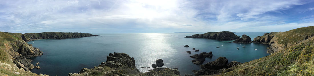 Panoramic view of sea by mountains against sky