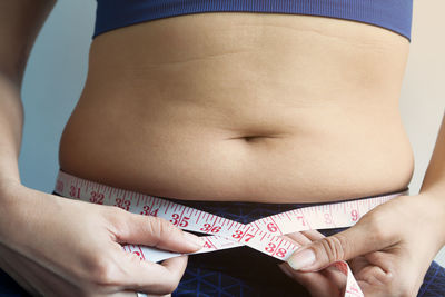 Midsection of woman measuring belly