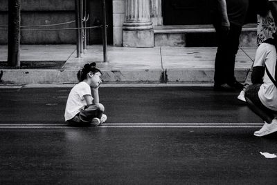 Rear view of people sitting on floor in city