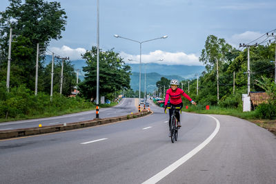 Rear view of man riding bicycle on road