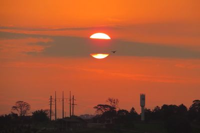 Low angle view of silhouette trees against orange sky