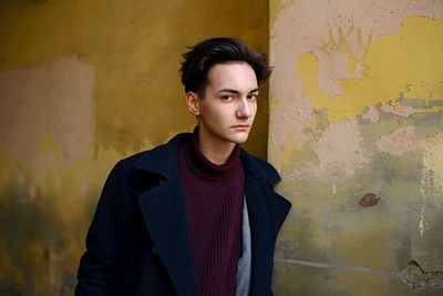 Portrait of young man standing against wall